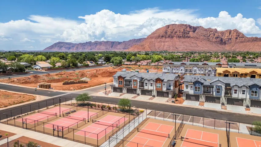 Multiple hard-surface courts, residential structures featuring varied facades, and a mountainous backdrop