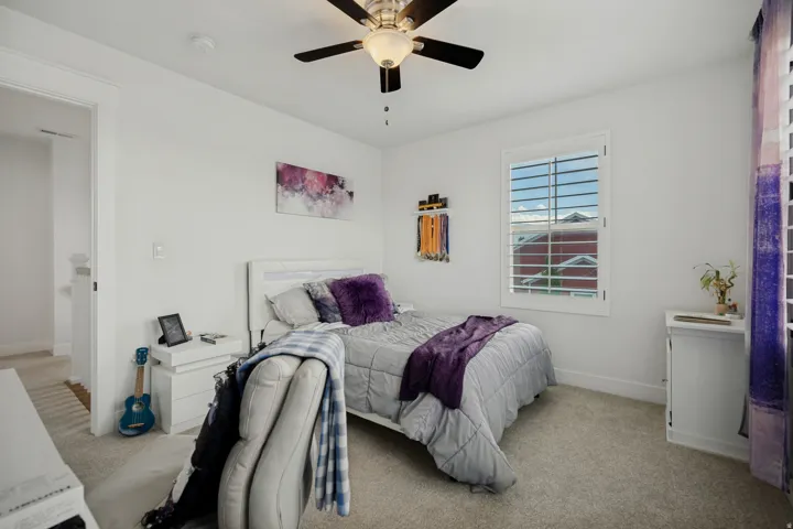 Carpeted flooring, white walls, ceiling fan with integrated lighting, window with white plantation shutters, and white trim throughout