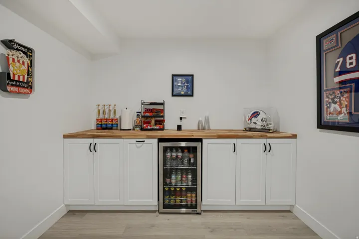 Built-in cabinetry with wood-finish countertops, undercounter beverage refrigerator, and light wood-finish flooring