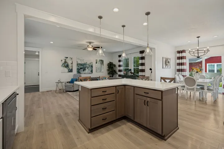 Kitchen island with integrated storage, light-toned wood-finish flooring, recessed lighting, and pendant light fixtures