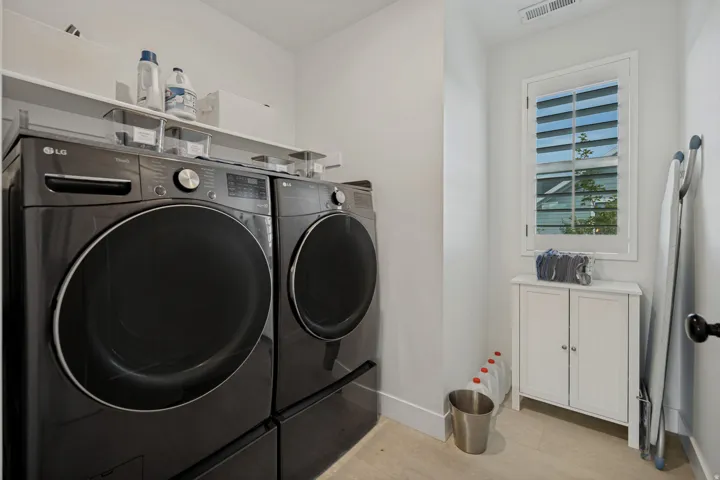 Dedicated laundry area featuring a window with integrated shutters, built-in cabinetry, and a fixed wall shelf