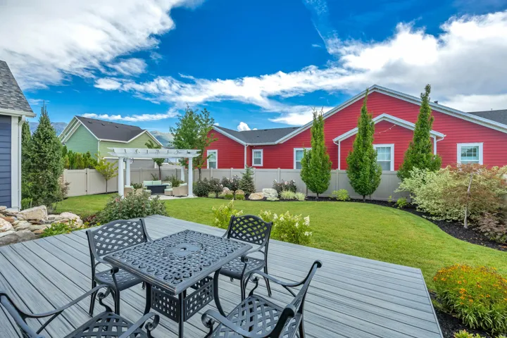 Expansive backyard featuring a composite deck, manicured lawn, and a white pergola