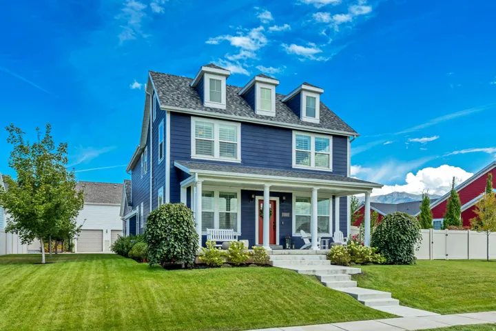 Two-story home with a blue siding exterior, a front porch with white pillars, and multiple dormer windows