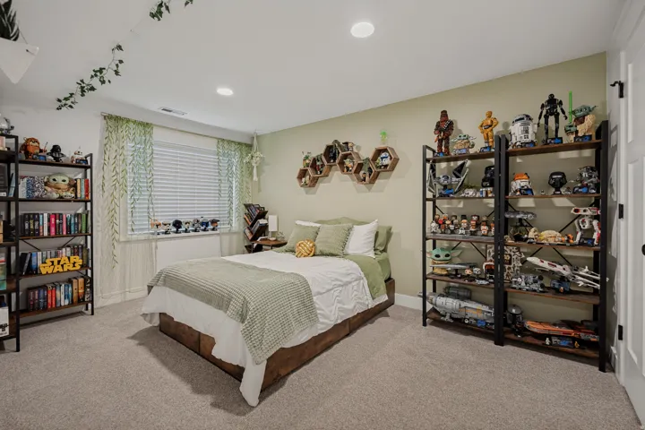 Recessed lighting illuminates the room, featuring a carpeted floor, window with blinds, and light-toned walls