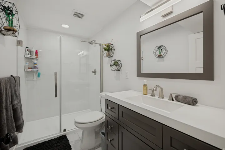 White vanity with an integrated rectangular sink, brushed nickel faucet, and a framed mirror
