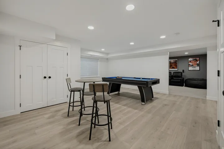 Expansive recreational space with wood-finish flooring, recessed lighting, and white paneled doors