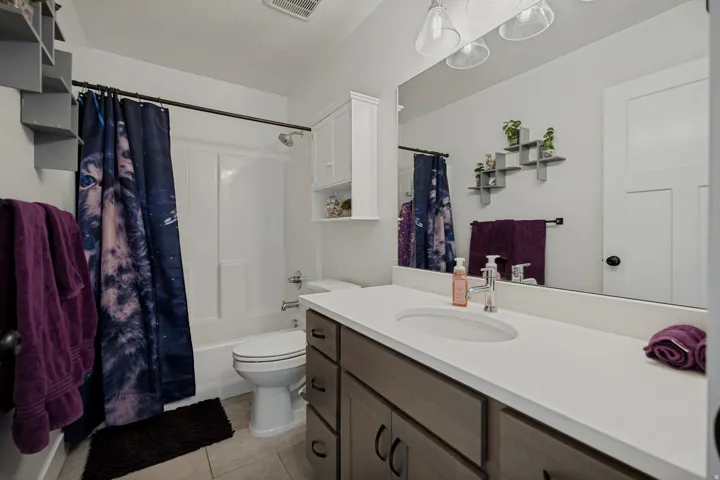 Bathroom featuring a vanity with an integrated sink, a white countertop, wood-finish cabinetry, and a shower-over-tub combination