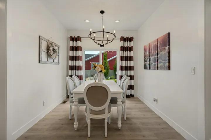 Recessed ceiling lighting, a contemporary chandelier, light wood-finish flooring, and white walls