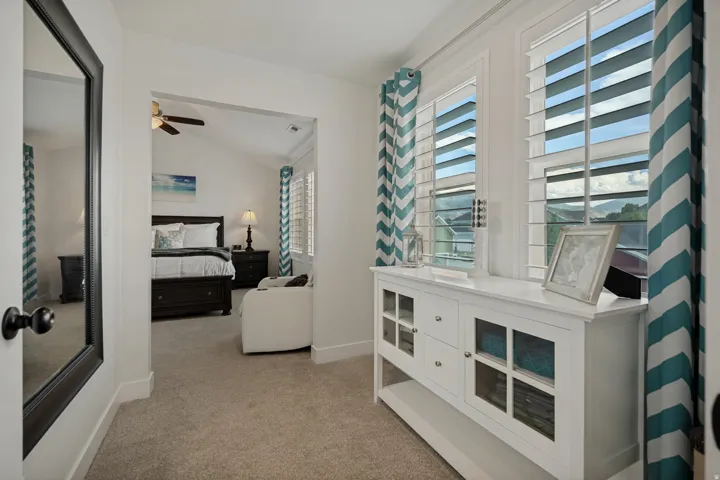 White built-in cabinetry with glass-front doors, plantation shutters, and light-toned carpeting