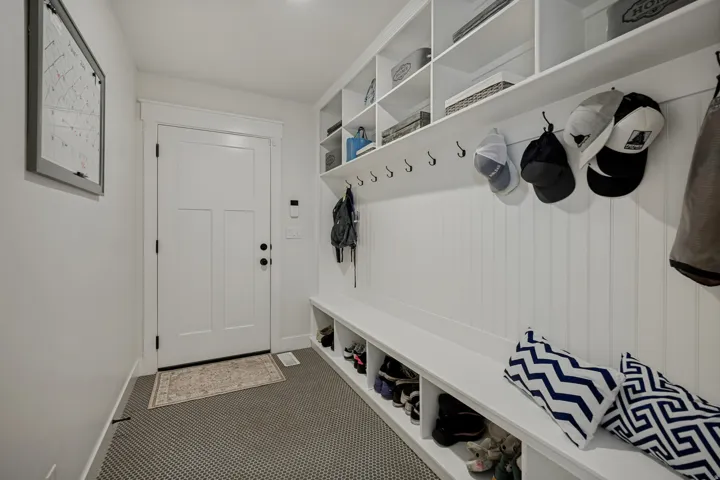 Built-in mudroom storage featuring white shelving, beadboard wall paneling, and a built-in bench with integrated cubbies