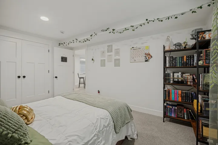 Recessed ceiling lighting illuminates the room, featuring white paneled doors and light gray carpeting