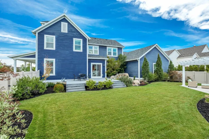 Expansive backyard featuring a manicured lawn, established landscaping, and a multi-level deck with steps