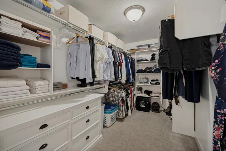 Walk-in closet featuring built-in cabinetry, shelving, hanging rods, and carpet flooring
