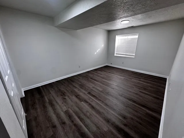 Dark wood-finish flooring, white trim, and a window with blinds