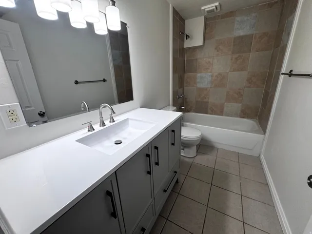 Integrated vanity with a rectangular sink, dual-handle faucet, and gray cabinetry