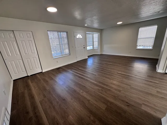Wood-finish flooring throughout, recessed ceiling lighting, and multiple windows with blinds