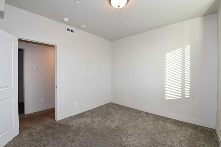 Wall-to-wall carpeting in a neutral tone, flush-mounted ceiling light fixture, and white painted walls