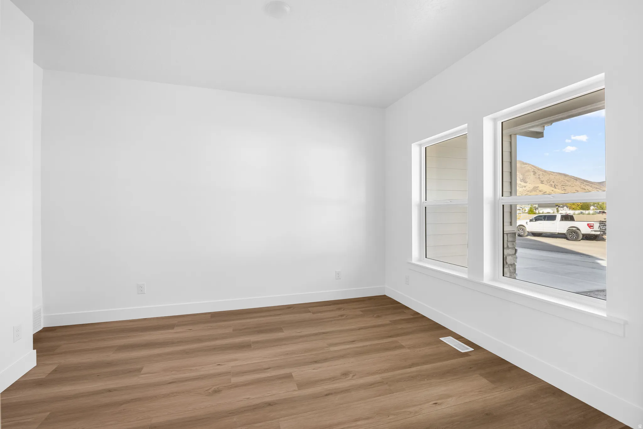 Bright interior with wood-finish flooring, white baseboards, multiple windows, and recessed ceiling lighting