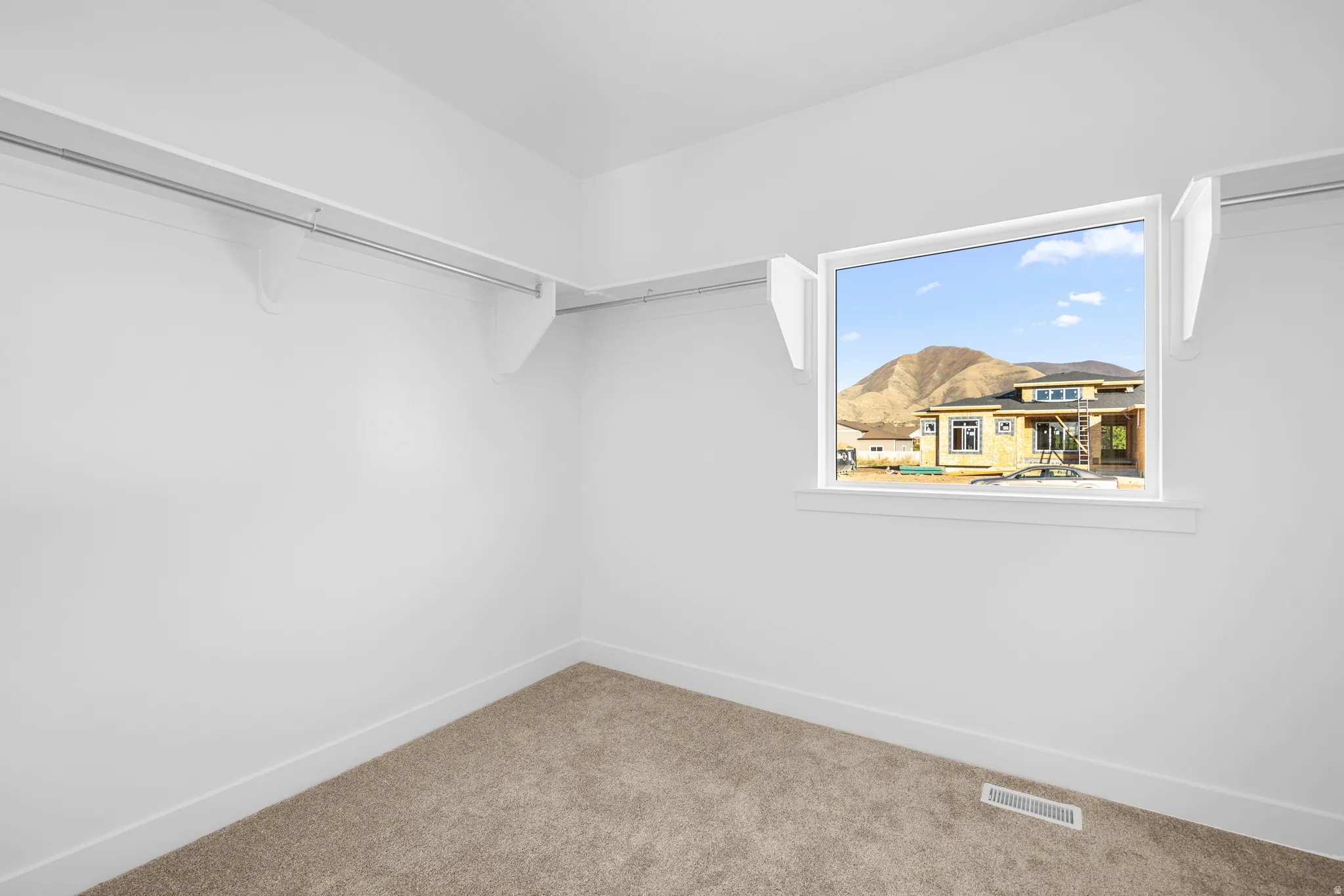 Carpeted flooring, white walls, built-in shelving, and a window with mountain scenery