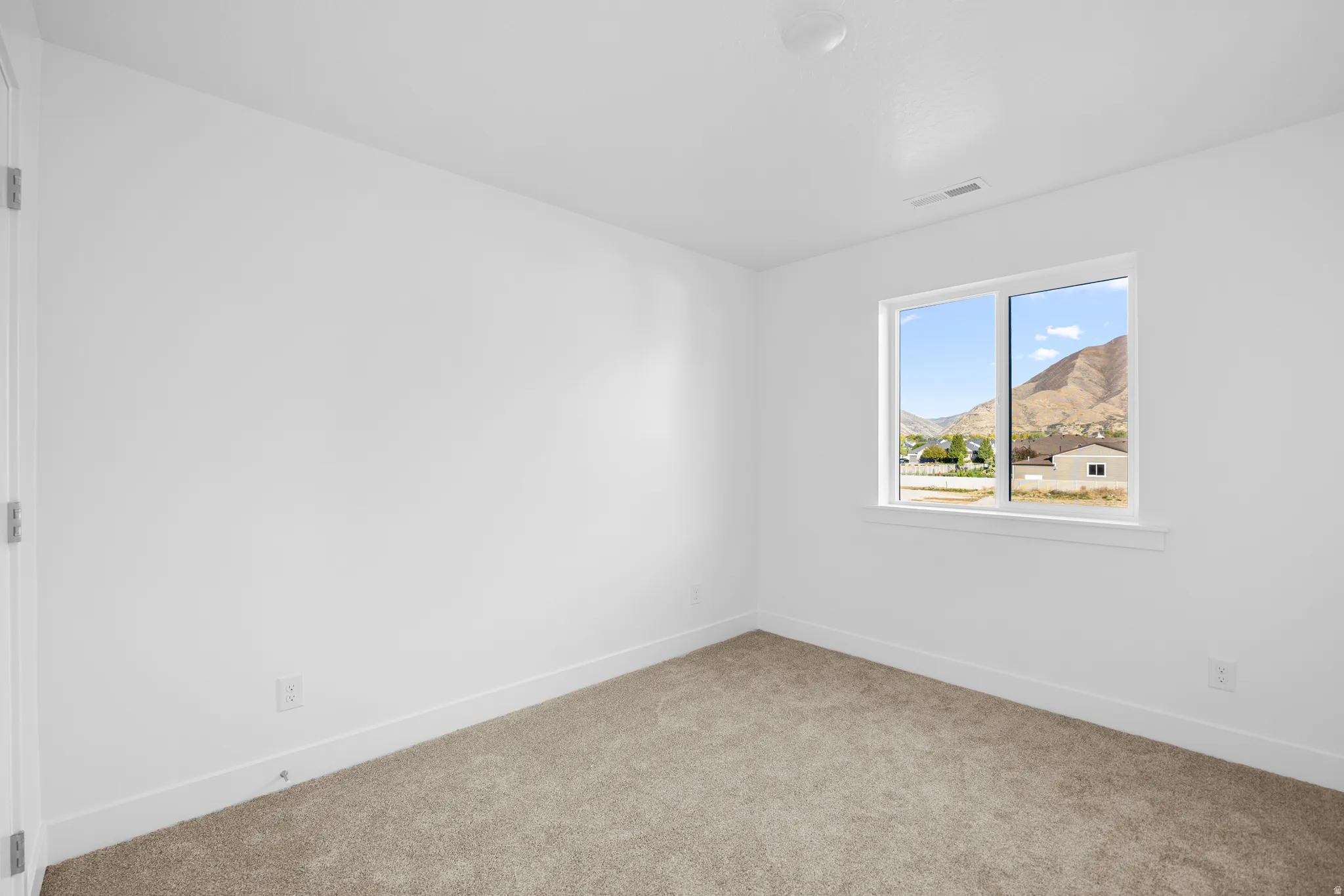 Bright corner bedroom flooded with natural light through dual-pane windows framing mountain vistas