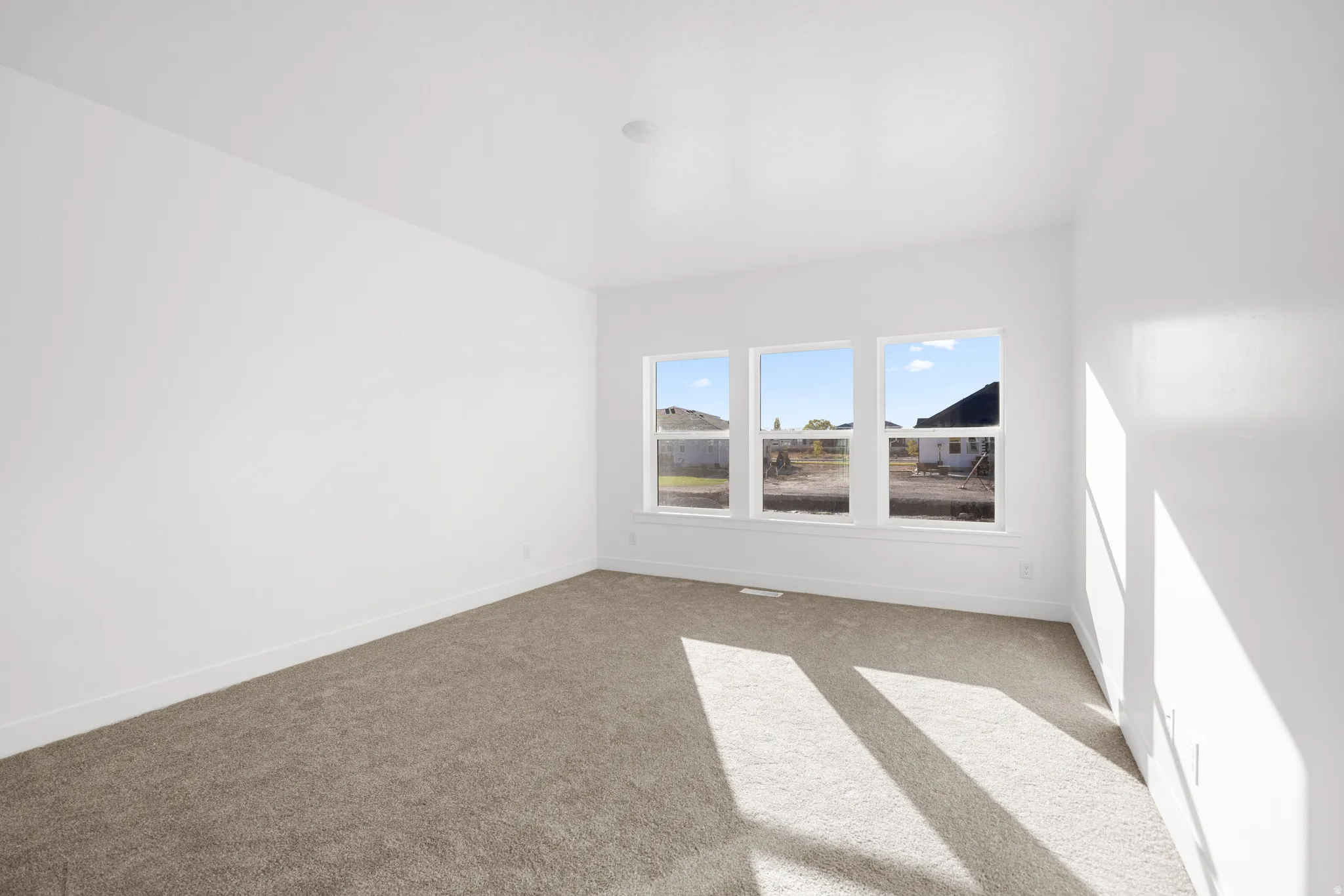 Neutral wall finishes, recessed ceiling lighting, and three large windows