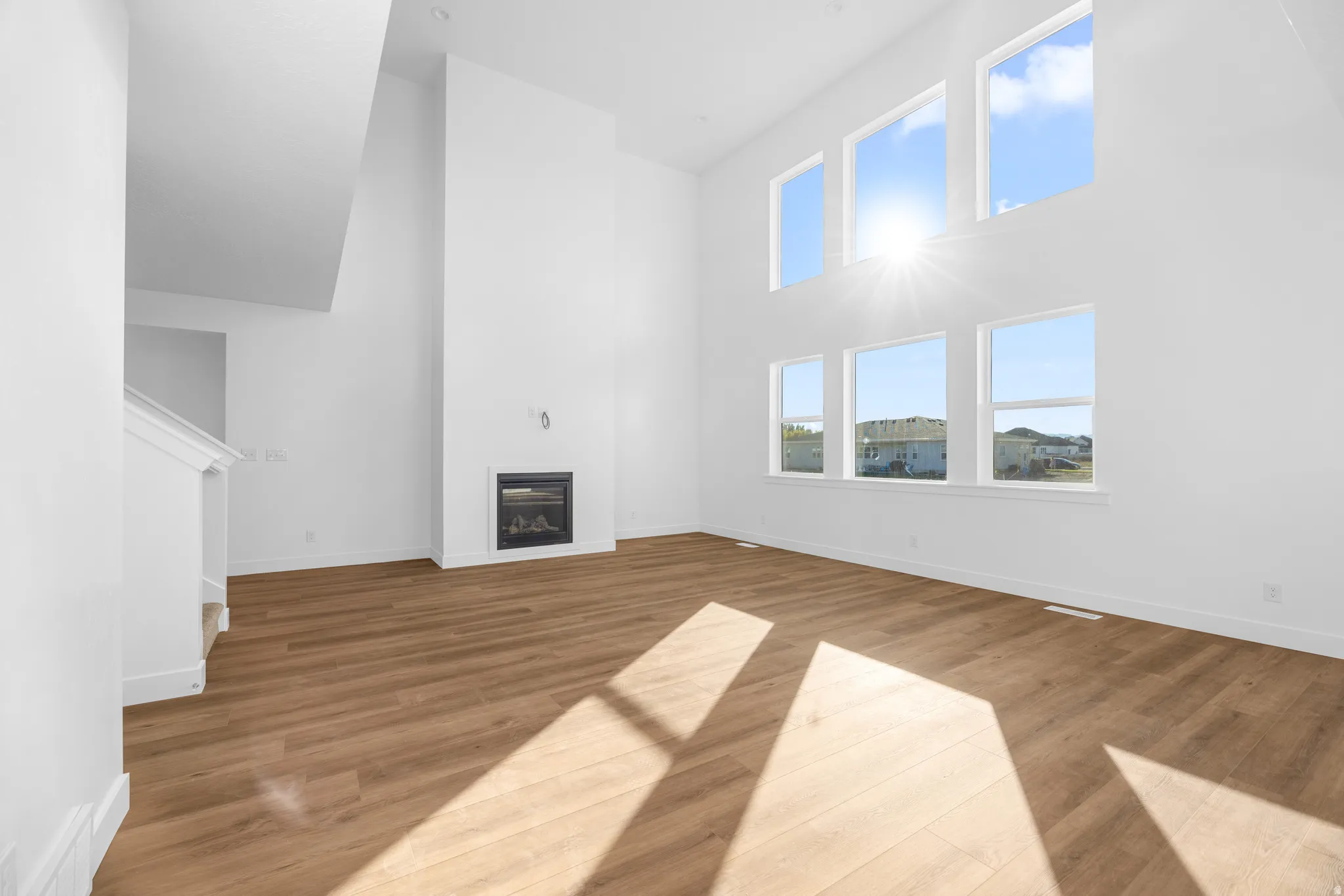 Spacious living area featuring high ceilings, wood-finish flooring, a built-in fireplace, and expansive windows