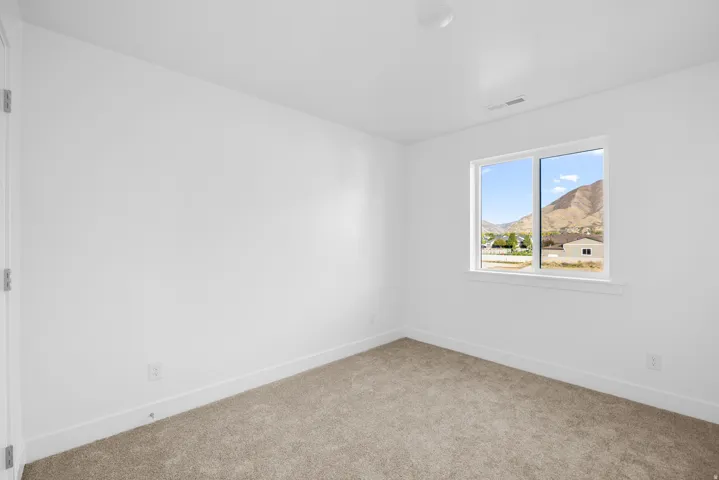 Bright corner bedroom flooded with natural light through dual-pane windows framing mountain vistas