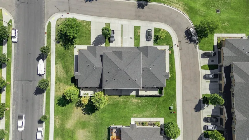 Paved street with sidewalks, gray shingle roofing, green lawn, and concrete driveways