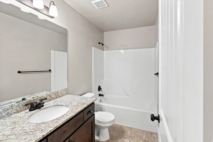 Bathroom featuring a single vanity with a granite-look countertop, undermount sink, and dark wood-finish cabinetry