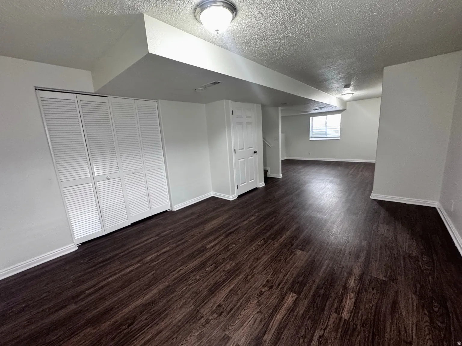 Expansive room featuring wood-finish flooring, white louvered closet doors, and recessed lighting