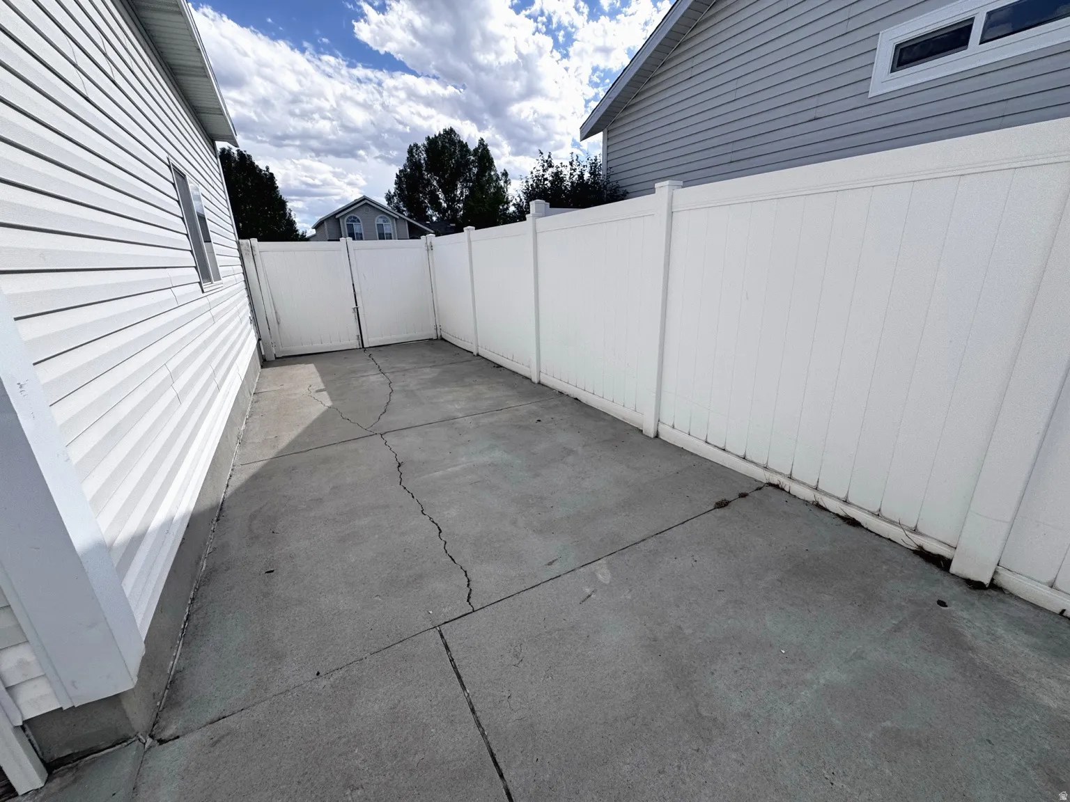 Paved concrete surface with white vinyl fencing and white vinyl siding