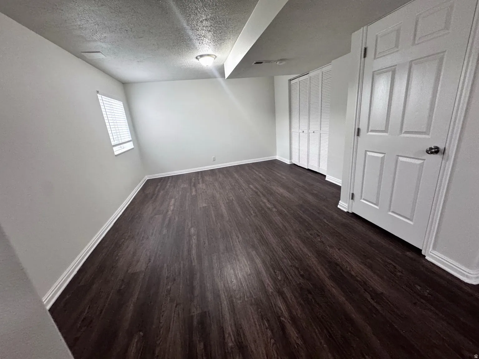 Wood-finish flooring, white walls, white trim, and white bi-fold closet doors