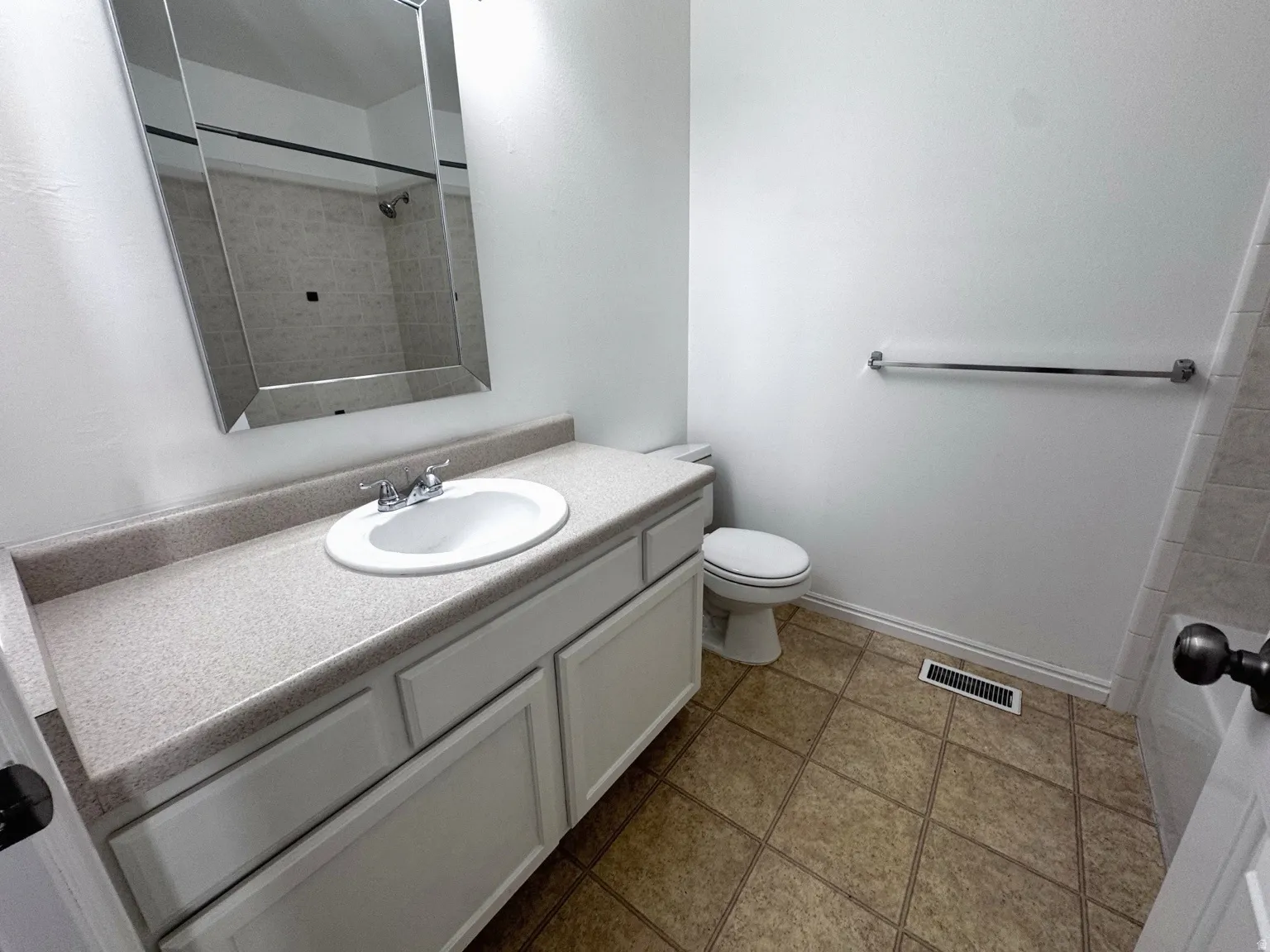 White vanity with a solid surface countertop, an undermount sink, and a chrome faucet