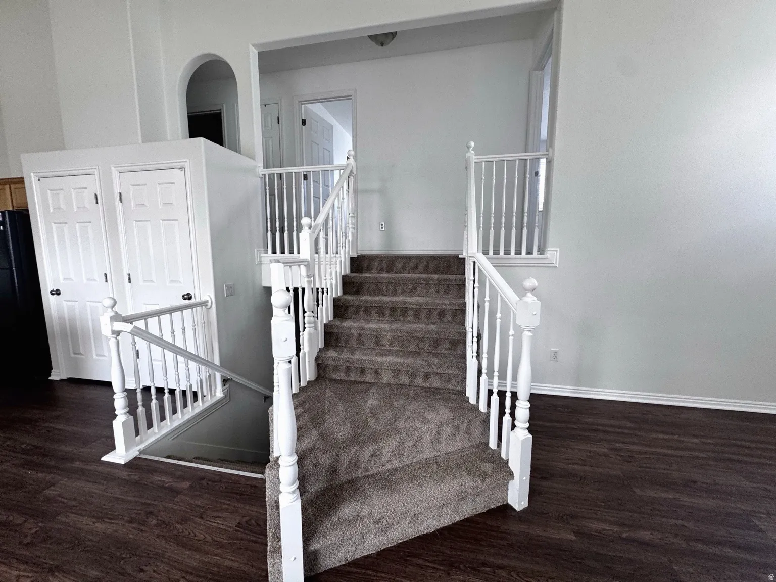 Staircase featuring white wood balusters and carpeted treads, with wood-finish flooring visible