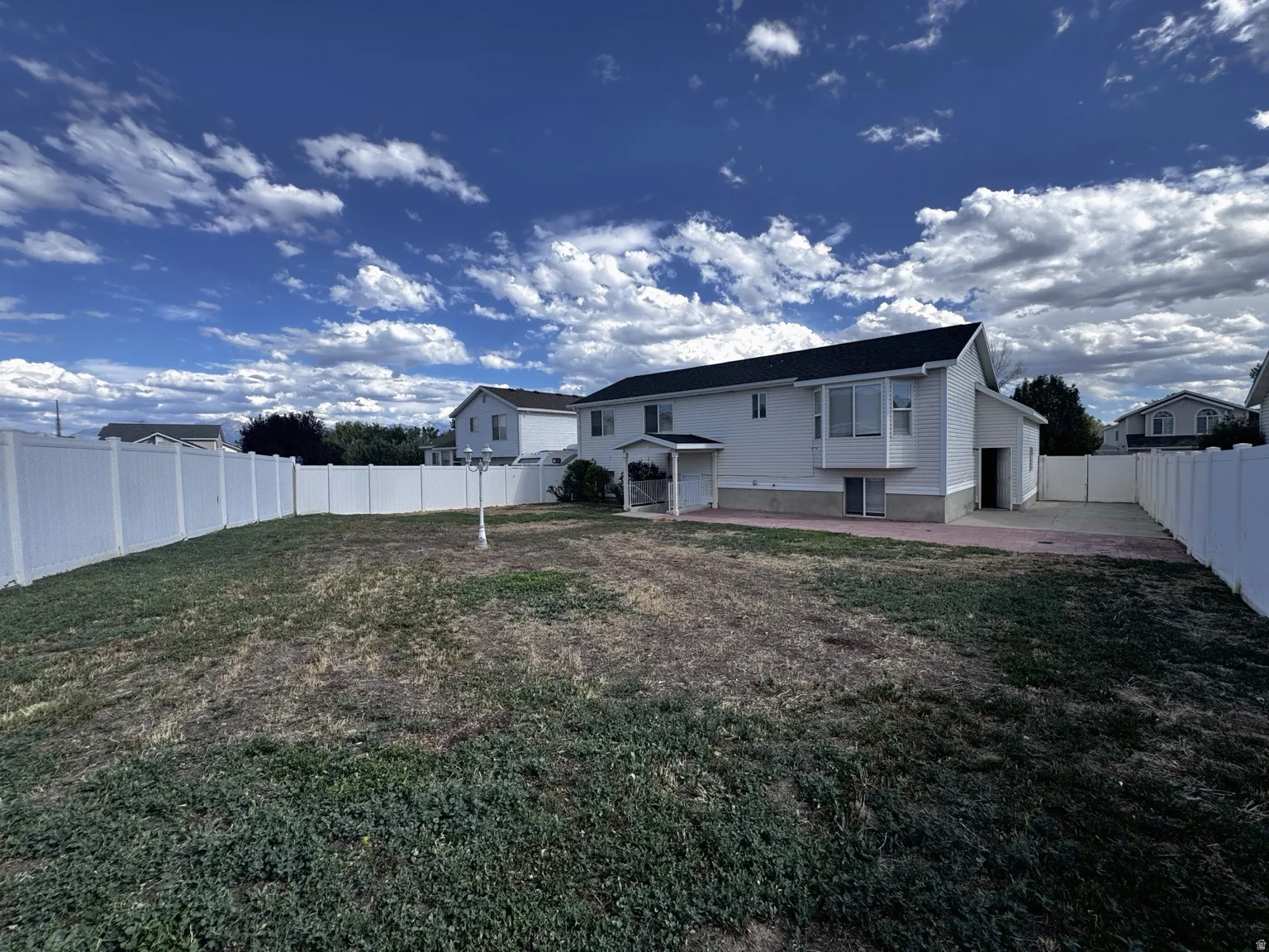 Expansive rear yard featuring white privacy fencing and a paved section