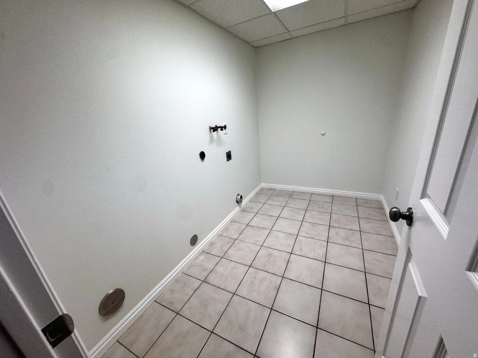 Tile flooring, white painted walls, and ceiling-mounted fluorescent lighting