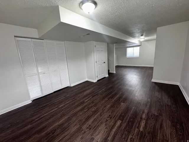 Expansive room featuring wood-finish flooring, white louvered closet doors, and recessed lighting