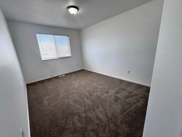 Carpeted flooring, neutral wall tones, window with horizontal blinds, and a flush-mount ceiling light fixture