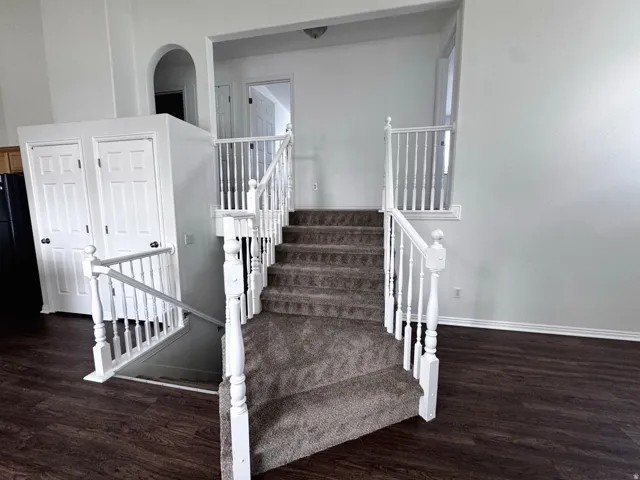 Staircase featuring white wood balusters and carpeted treads, with wood-finish flooring visible