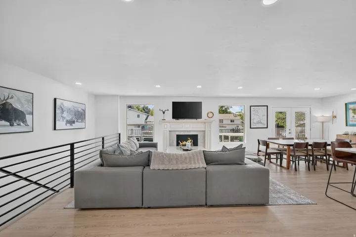 Bright living area featuring wood-finish flooring, a decorative fireplace with a mantel, and recessed lighting