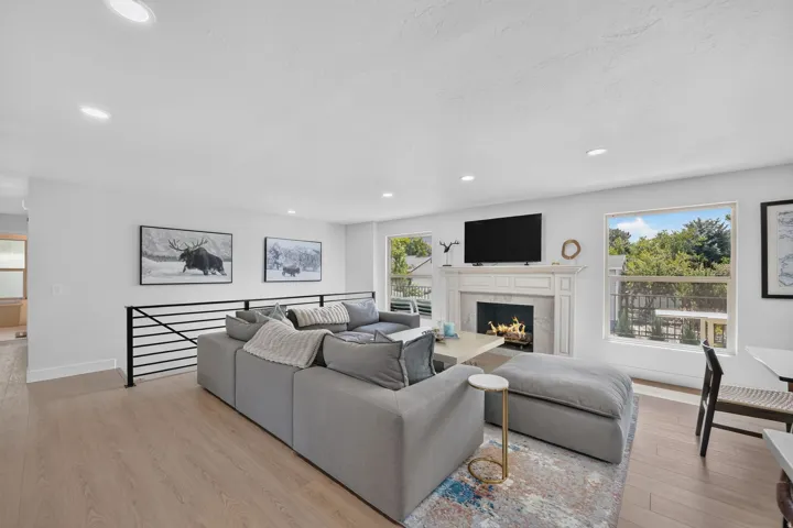 Open-concept living area featuring wood-finish flooring, recessed lighting, and a white fireplace surround