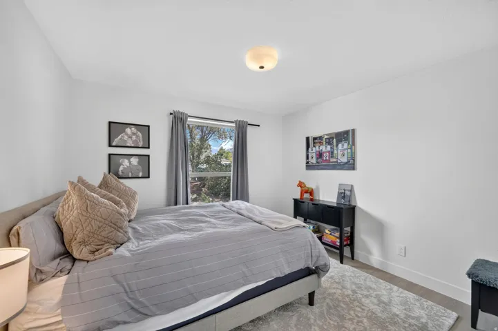 Recessed window with dark curtain rods, light wood-finish flooring, and a ceiling-mounted semi-flush light fixture