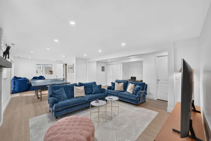 Recessed lighting illuminates an expansive open-concept room with light wood-finish flooring