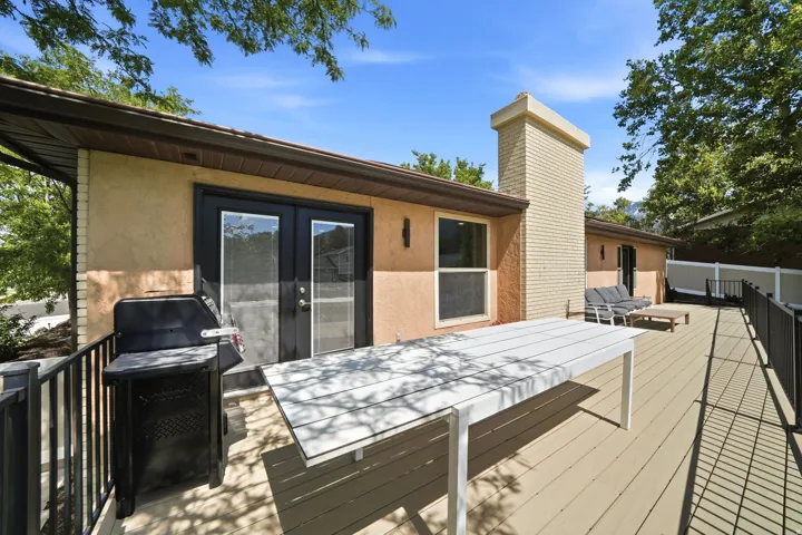 Expansive outdoor deck featuring composite decking, black metal railings, and a stucco exterior with a brick chimney