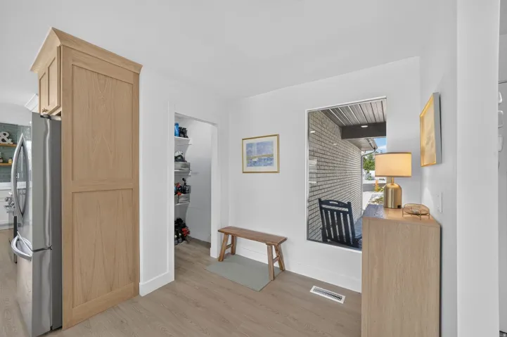 Built-in pantry cabinetry, stainless steel refrigerator, wood-finish flooring, and a large window