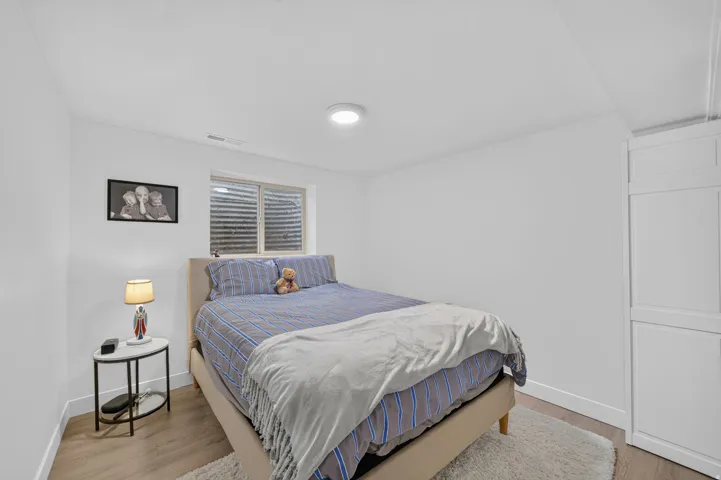 White walls with wood-finish flooring, a ceiling-mounted light fixture, and a built-in white wardrobe