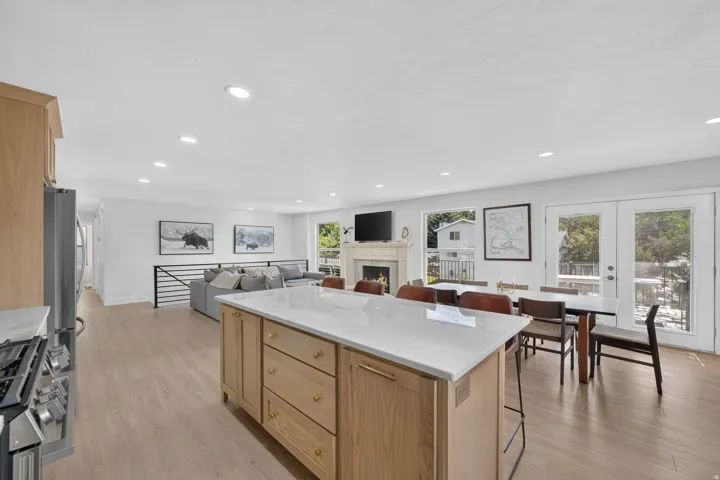Open concept living area with wood-finish flooring, a kitchen island with stone countertop, and direct access to an outdoor area through double doors