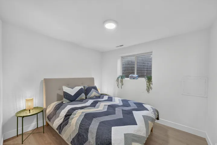 Recessed window with blinds, wood-finish flooring, and a flush-mount ceiling light