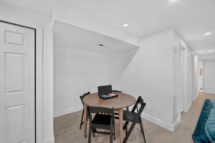 Recessed lighting, light wood-finish flooring, white panel door, and crisp white walls