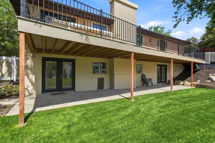Expansive lawn with a concrete patio, brick facade, and multiple ground-level entryways